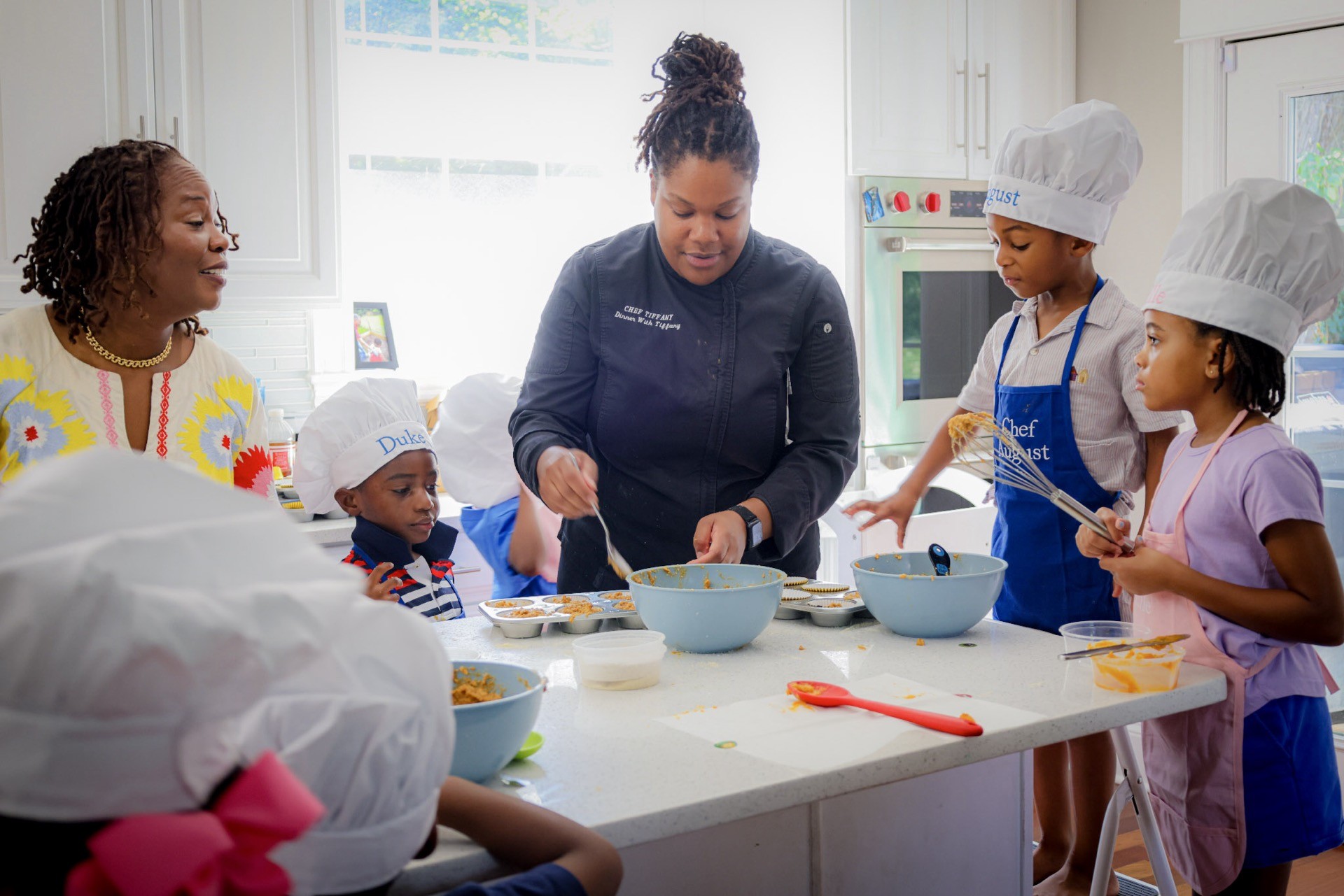 A chef guides children in a cooking class